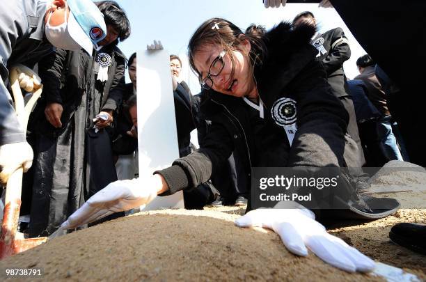 Relatives of a deceased sailor of the sunken South Korean naval vessel Cheonan cries as she touches grave during the funeral ceremony at the Daejeon...