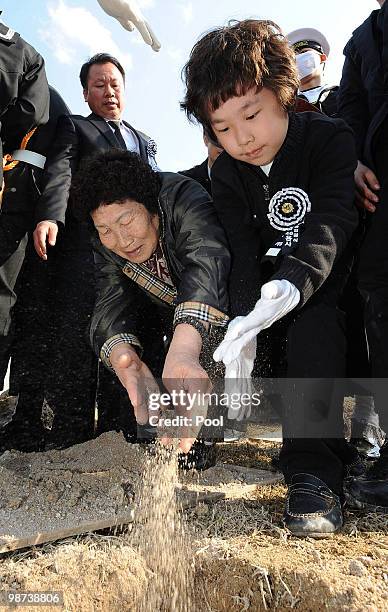 Relatives of a deceased sailor of the sunken South Korean naval vessel Cheonan sprinkle earth on remains during the funeral ceremony at the Daejeon...