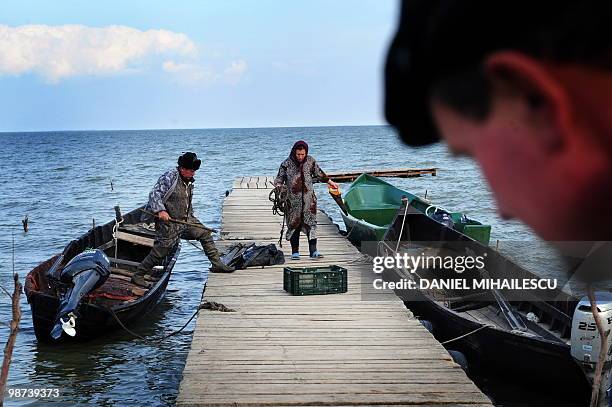 Isabelle WESSELINGH A Lipovan fisherman is helped by his wife as he unloads belongings from his boat on lake Razelm in Sarichioi village, 250kms east...