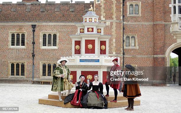Actors dressed in historical costumes pose during a photocall at the newly unveiled wine fountain in the inner courtyard at Hampton Court Palace on...