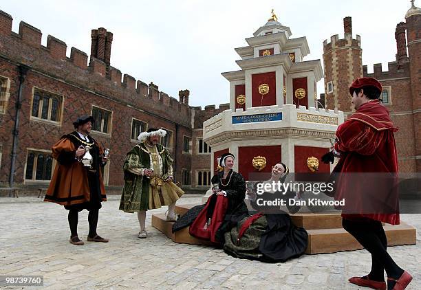 Actors dressed in historical costumes pose during a photocall at the newly unveiled wine fountain in the inner courtyard at Hampton Court Palace on...