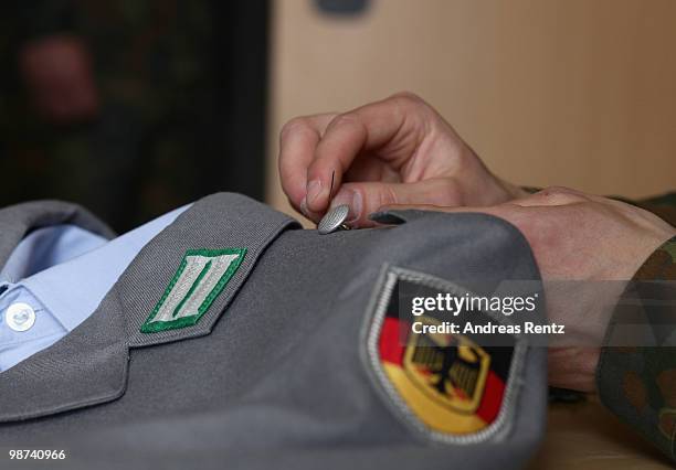 Young recruit of the German Bundeswehr is sewing on a button on his jacket in his living room during his nine months military service at the Julius...