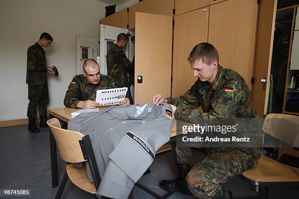 The young recruit Gaburek of the German Bundeswehr is sewing on a button on his jacket as young recruit Koenig is reading in their living room during...