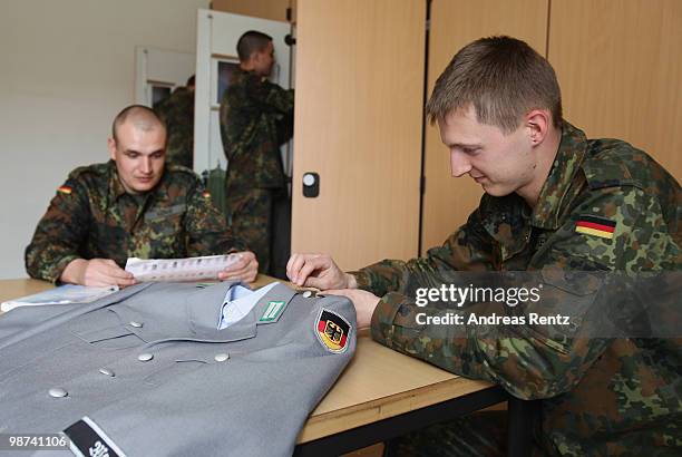 The young recruit Gaburek of the German Bundeswehr is sewing on a button on his jacket as young recruit Koenig is reading in their living room during...