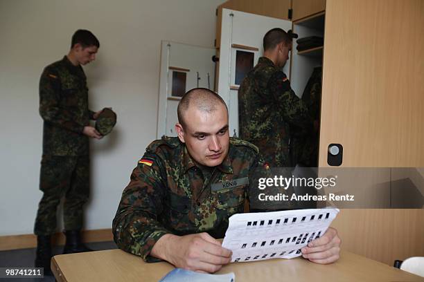 The young recruit Koenig of the German Bundeswehr is reading while his mates get dressed in their living room during their nine months military...