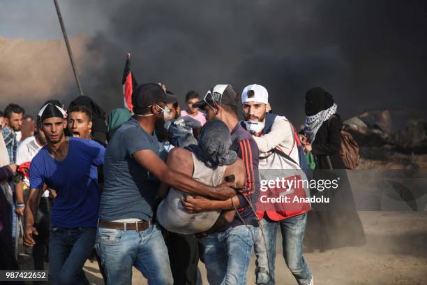Palestinian paramedics carry an injured protestor after Israeli forces intervene them on the 14th week of right of return march near Al Bureij...