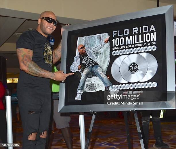 Rapper Flo Rida poses next to a platinum plaque for selling more than 100 million singles during his memorabilia case dedication at the Hard Rock...