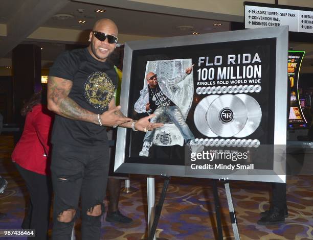 Rapper Flo Rida poses next to a platinum plaque for selling more than 100 million singles during his memorabilia case dedication at the Hard Rock...