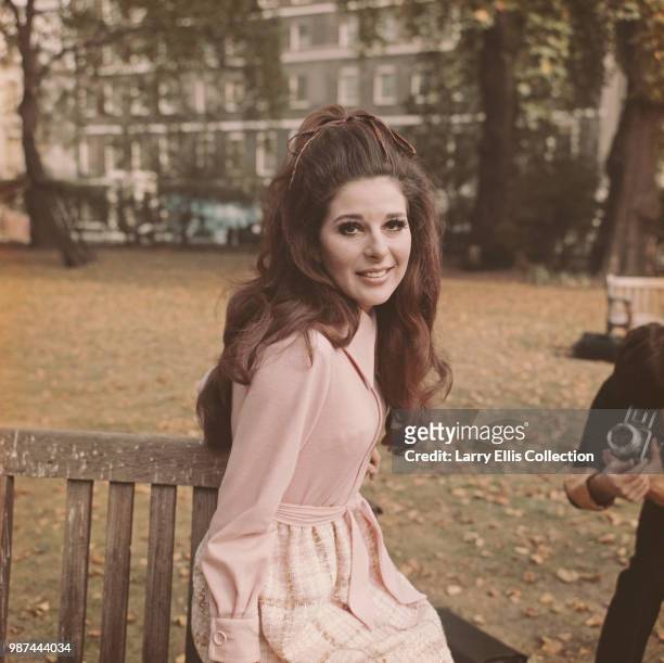 American singer and songwriter Bobbie Gentry posed sitting on a park bench in a London square on 13th October 1969.