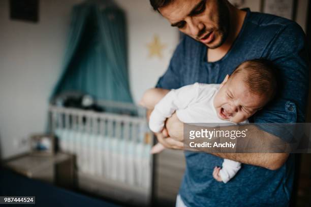 papa holding huilende baby in de koliek carry - baby stockfoto's en -beelden