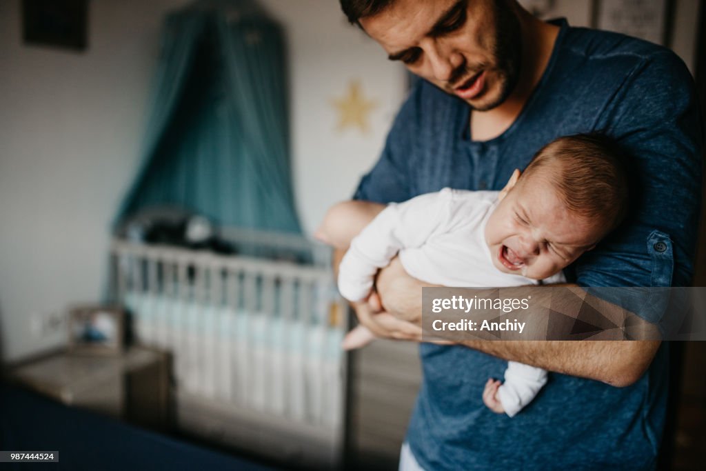 Dad Holding crying baby in the colic carry