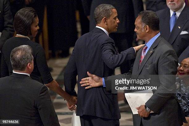 President Barack Obama pats Reverend Jesse Jackson on the back as he reaches out to shake hands with First Lady Michelle Obama at the funeral service...
