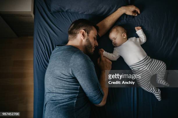 pasgeboren babyjongen slapen met zijn vader op bed - sleeping baby stockfoto's en -beelden