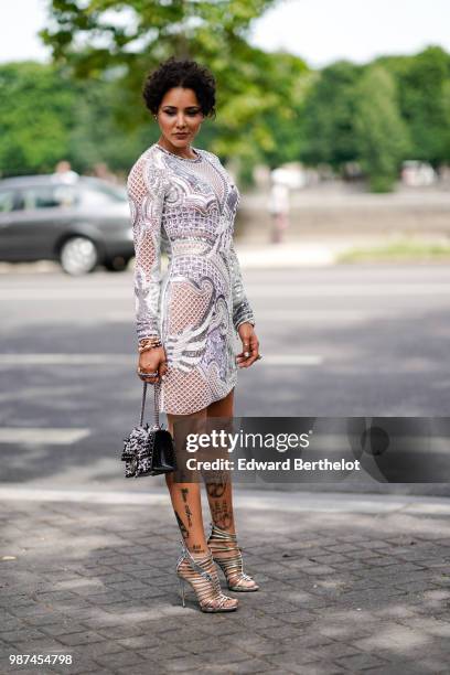 Guest wears a silver and white mesh dress, a studded bag, silver metallic shoes, outside Balmain, during Paris Fashion Week - Menswear Spring-Summer...