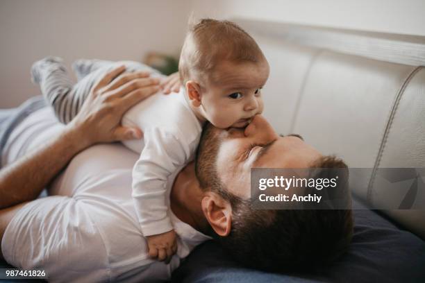 vader spelen in bed met zijn kleine babyjongen - baby with parents stockfoto's en -beelden