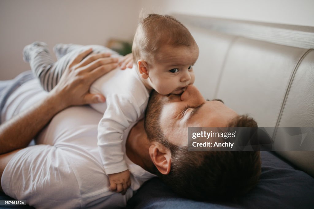 Father playing in bed with his little baby boy