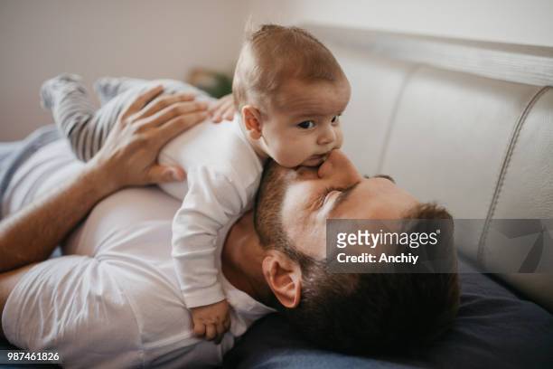 father playing in bed with his little baby boy - new stock pictures, royalty-free photos & images