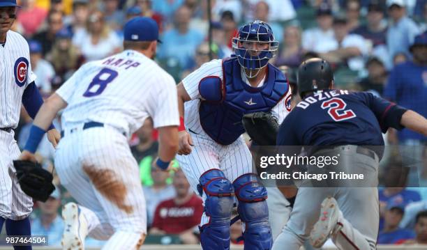 Chicago Cubs catcher Chris Gimenez, middle, watches as third baseman Ian Happ chases down the Minnesota Twins' Brian Dozier at home plate in the...