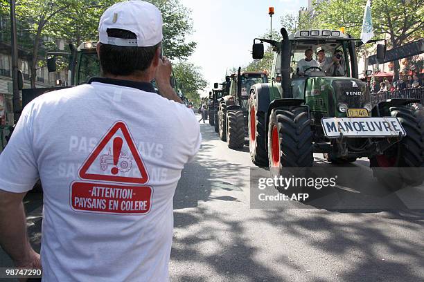 French farmer wearing a shirt reading "Caution, angry farmers" takes a picture of tractors driving in Paris on April 27, 2010 during a demonstration...