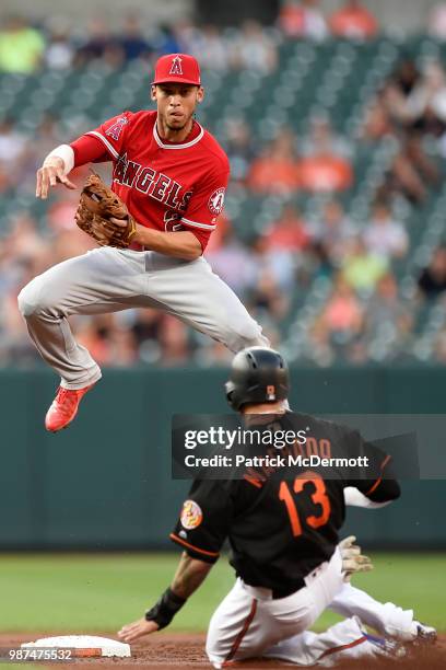 Andrelton Simmons of the Los Angeles Angels of Anaheim jumps over Manny Machado of the Baltimore Orioles as he turns a double play in the first...