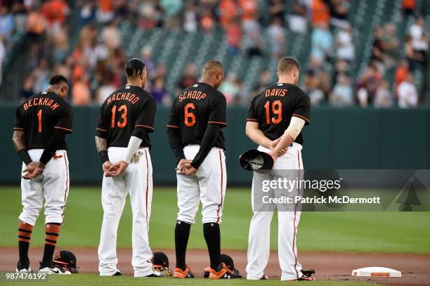 Tim Beckham, Manny Machado, Jonathan Schoop, and Chris Davis of the Baltimore Orioles stand during a moment of silence for the five victims of the...