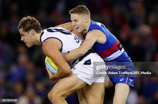 Jake Kolodjashnij of the Cats is tackled by Lachie Hunter of the Bulldogs during the 2018 AFL round 15 match between the Western Bulldogs and the...