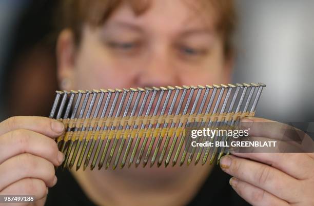 Diane Brogdon, a machine operator for eighth years at the Mid Continent Nail Corporation, looks at a set of nails that fit into a nail gun at the...