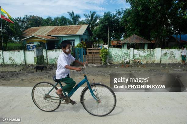 In this picture taken on June 28, 2018 an ethnic Rakhine boy rides a bicycle in front of Inn Din police station in Rakhine state. - Fewer than 200...