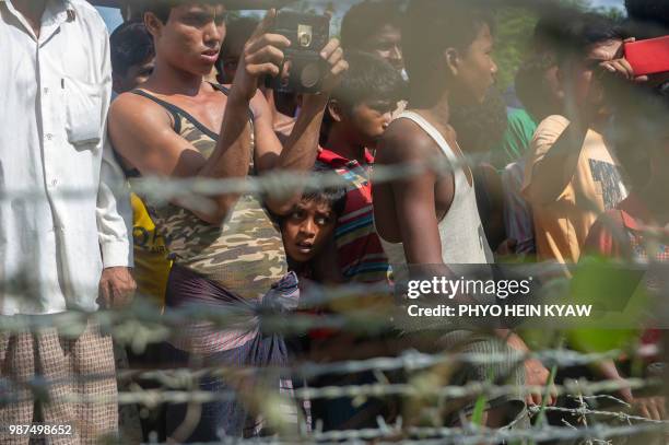 Rohingya refugees gather near the fence in the "no man's land" between Myanmar and Bangladesh border as seen from Maungdaw, Rakhine state, on June...