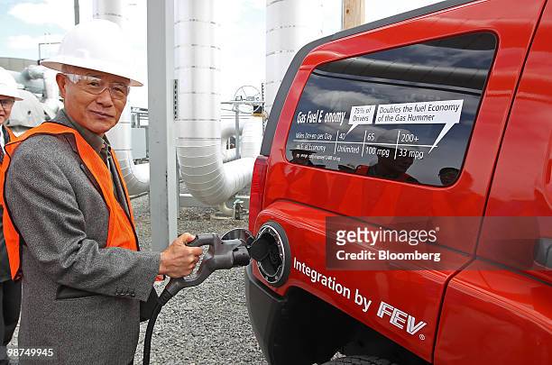 Keh-Sik Min, vice-chairman and chief executive officer of Hyundai Heavy Industries Co. Ltd., plugs in to charge a Raser Technologies Inc. Plug-in...