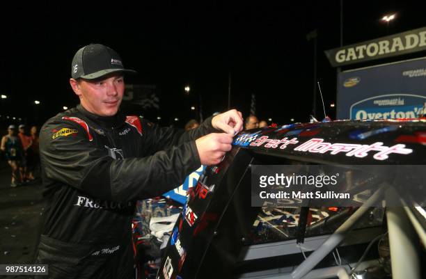 Brett Moffitt, driver of the Fr8Auctions.com Toyota, applies the winner's sticker in Victory Lane after the NASCAR Camping World Truck Series...