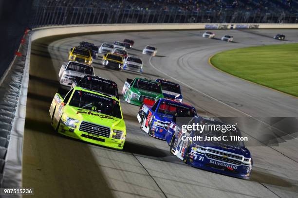 Matt Crafton, driver of the Shasta/Menards Ford, and Johnny Sauter, driver of the ISM Connect Chevrolet, lead a pack of trucks during the NASCAR...