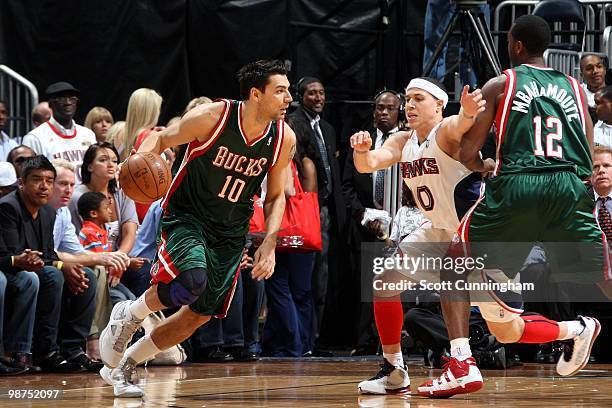 Carlos Delfino of the Milwaukee Bucks looks to move the ball on a screen set up by teammate Luc Mbah a Moute against MIke Bibby of the Atlanta Hawks...