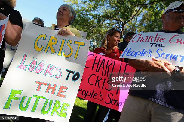 People hold signs as Florida Gov. Charlie Crist announces that he will make an independent bid for the open U.S. Senate seat on April 29, 2010 in St....