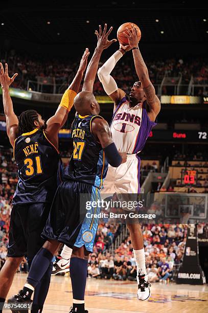 Amar'e Stoudemire of the Phoenix Suns shoots over Johan Petro and Nene of the Denver Nuggets at U.S. Airways Center on April 13, 2010 in Phoenix,...