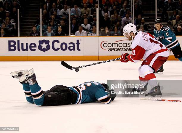 Dan Cleary of the Detroit Red Wings controls the puck while Devin Setoguchi of the San Jose Sharks lies injured on the ice in Game One of the Western...