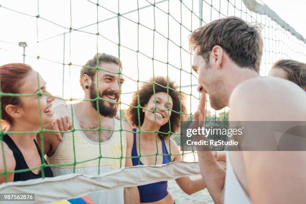 hombre alegre saludando a sus amigos detrás de la red del voleibol - campeón de torneo fotografías e imágenes de stock