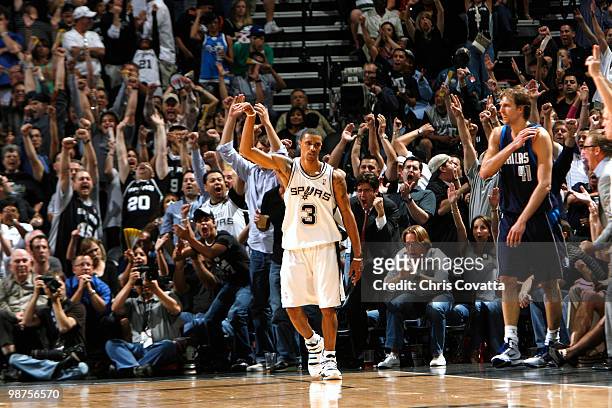 Fans cheer after George Hill of the San Antonio Spurs sinks a 3-pointer while being defended by Dirk Nowitzki of the Dallas Mavericks in Game Six of...