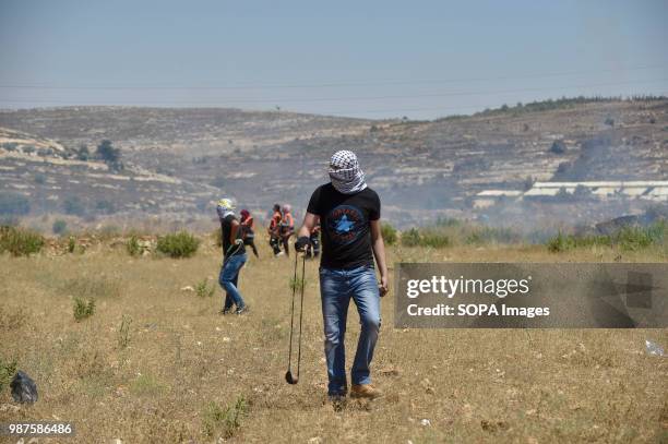 Palestinian protesters use slings to hurl rocks and bottles at Israeli forces during clashes near Beit El on the outskirts of the West Bank city of...