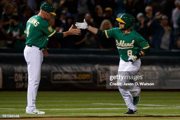 Jed Lowrie of the Oakland Athletics is congratulated by third base coach Matt Williams after hitting a home run against the Cleveland Indians during...