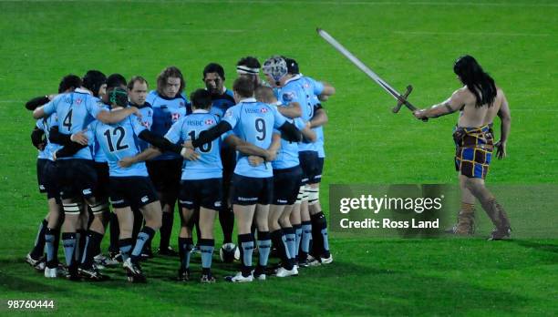 The Waratahs huddle on the field as the Highlander mascot circles prior to the round 12 Super 14 match between the Highlanders and the Waratahs on...