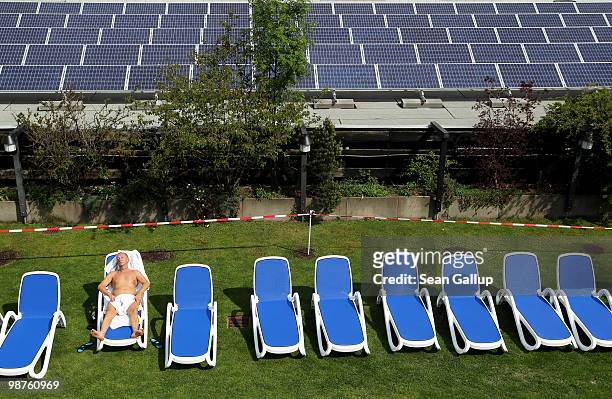Man sunbathes at a rooftop spa next to solar cell panels on April 30, 2010 in Berlin, Germany. Germany has invested heavily in solar and other...