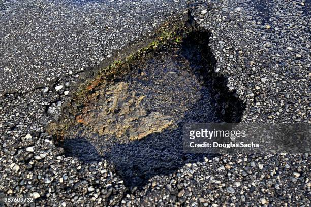pothole in the asphalt paved road - pothole stockfoto's en -beelden