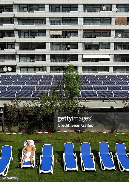 Man sunbathes at a rooftop spa next to solar cell panels on April 30, 2010 in Berlin, Germany. Germany has invested heavily in solar and other...