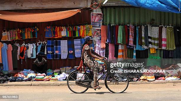 Sri Lankan woman cycles past a roadside market in the northern town Jaffna on April 30, 2010. The Central Bank opened two financial company branches...
