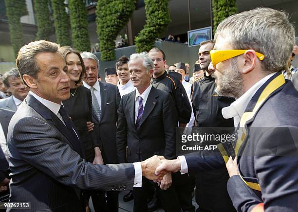 French President Nicolas Sarkozy , shakes hand with an unidentified staff member, next to his wife Carla Bruni-Sarkozy and French actor Alain Delon...