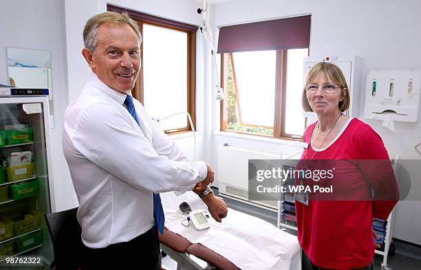 Former Prime Minister Tony Blair rolls up his sleeve to have his blood pressure taken by Nurse Paula Martin during a visit to Alexandra Avenue Health...