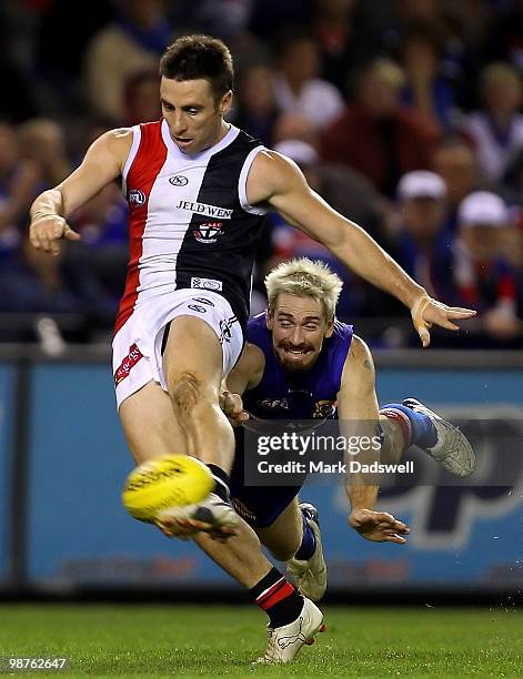 Stephen Milne of the Saints kicks under pressure from Jason Akermanis of the Bulldogs during the round six AFL match between the Western Bulldogs and...