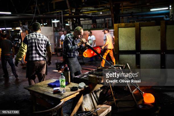 glass blower working with blowpipe on glowing glass in glass factory - blowgun stock pictures, royalty-free photos & images