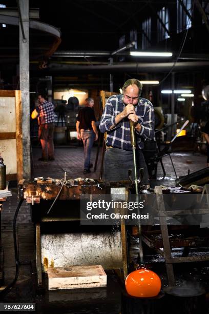 glass blower working with blowpipe on glowing glass in glass factory - blowgun stock pictures, royalty-free photos & images